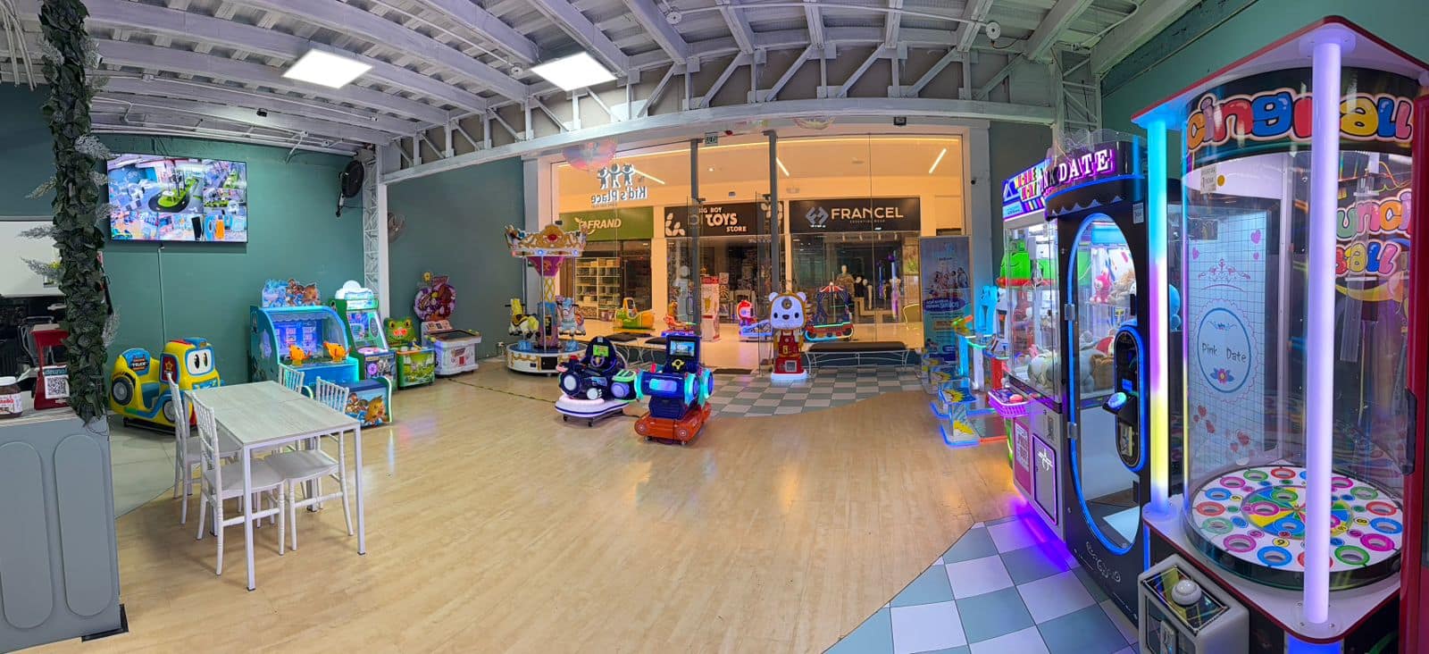 Zona de arcade con máquinas de video, grúas de peluches, kiddie rides y carrusel